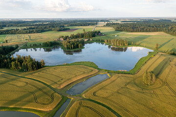 Beautiful aerial view of a serene lake surrounded by green fields and trees