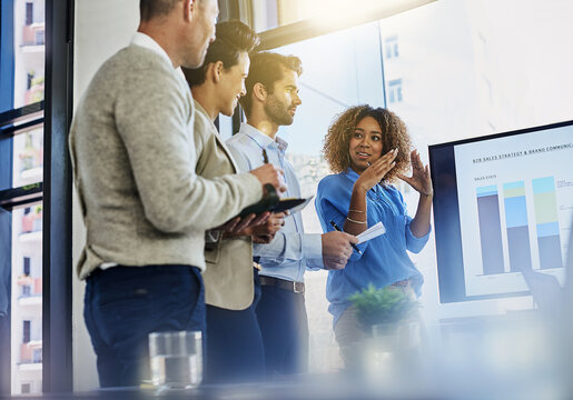 Business woman, screen or meeting with team for analytics, statistics or performance in office. Female person, employee or discussion with display, graph or chart for review or company improvement - Powered by Adobe