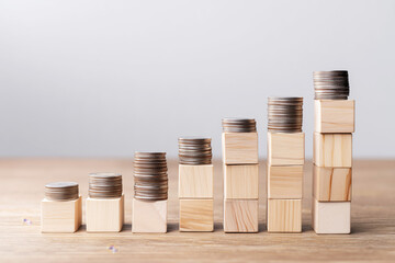 Wooden Blocks and Coins Forming Upward Steps for Income Growth