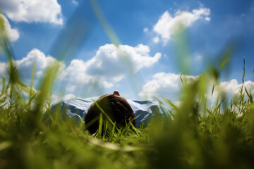 Person Lying on Grass Looking at Sky with Clouds Above