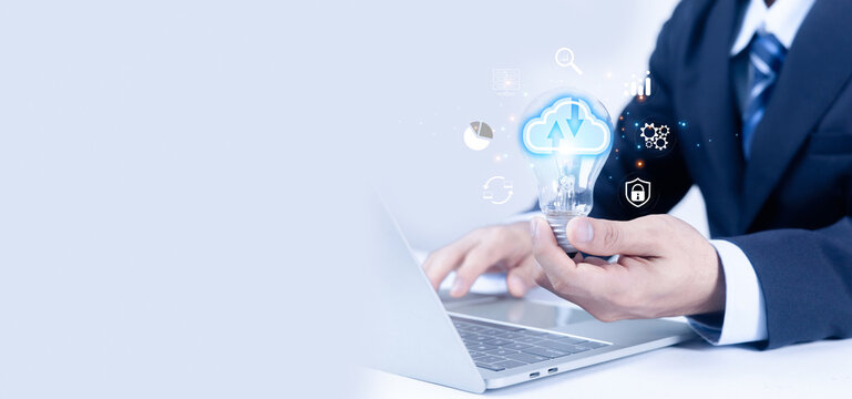 Businessman using laptop holding light bulb with cloud computing icons, data analytics, cybersecurity and digital technology concept, representing innovation, smart business solutions. - Powered by Adobe