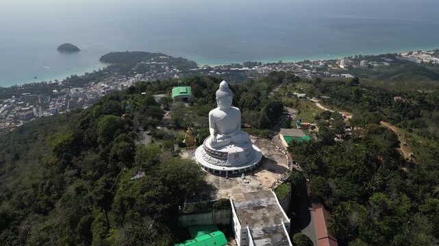 Descending half-orbit drone shot approaching the white marble Big Buddha. Features breathtaking views of the Andaman Sea and Phuket's tropical coast in the background. 4K cinematic travel footage.