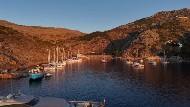 Saronic Gulf,Hydra Island,Aerial view backwards from the beach club in middle of Mandraki Bay over big motor yacht and some boats towards the entrance of the bay early in the morning.