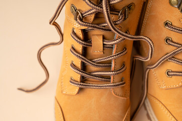 Stylish youth children's yellow men's boots made of genuine leather with laces on beige background top view. Rough-soled boots, work shoes, travel footwear close-up. Stylish nubuck shoes