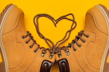 Stylish youth children's yellow men's boots made of genuine leather with laces on yellow background top view. Rough-soled boots, work shoes, travel footwear. Stylish nubuck shoes