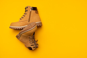 Stylish youth children's yellow men's boots made of genuine leather with laces on yellow background top view. Rough-soled boots, work shoes, travel footwear. Stylish nubuck shoes