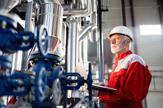 Senior engineer inspecting industrial plant operations using laptop - Powered by Adobe