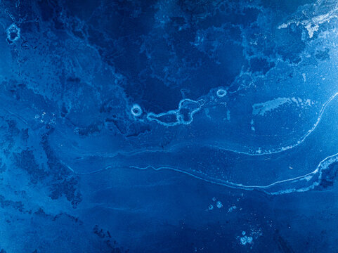 Aerial view of swirling sapphire patterns creating a mesmerizing dance of light and shadow across the water's surface, Caledonian Forest, Cairngorms National Park, Scotland.