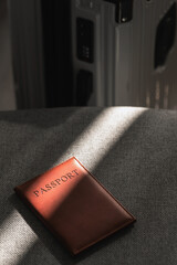 Leather passport on sofa with modern suitcase in natural light