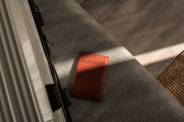 Leather passport on sofa with modern suitcase in natural light
