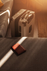 Leather passport on sofa with modern suitcase in natural light