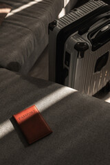Leather passport on sofa with modern suitcase in natural light