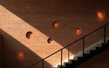 Sunlight streams across textured brick wall with circular openings