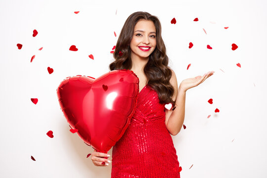 A beautiful young woman with heart shape air balloon on a white background. Woman on Valentine's Day. Symbol of love
