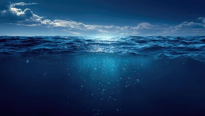 Deep blue ocean with sunlight shimmering on the surface and bubbles below
