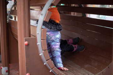 Child on playground in cold weather. Play area in the park. Outdoor playground.