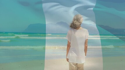 woman standing at water's edge, with animated green-white-green flag blending over tech scene - Powered by Adobe