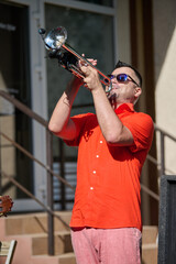 Adult man playing trumpet outside in bright daylight © TRAVELARIUM