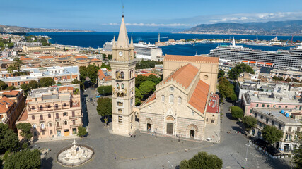Fototapeta premium Aerial view of the Cathedral Basilica of Santa Maria, located in the historic center of Messina, Sicily, Italy. The Calabrian coast, separated by the Strait of Messina, is silhouetted on the horizon.