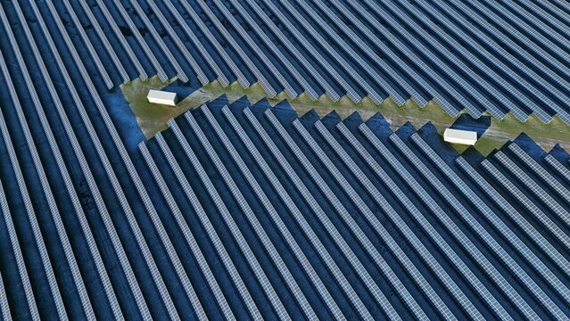 Aerial view of rows of solar panels reflecting the sky, interspersed with green grass and small white buildings, Wellingborough, England, United Kingdom.