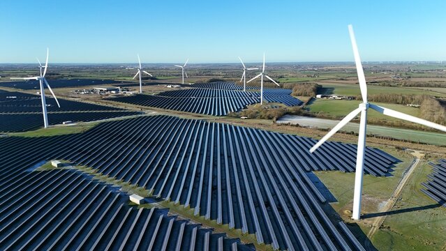 Aerial view of solar arrays and wind turbines stand in stark contrast against the winter fields under a cold, clear sky, Wellingborough, England, United Kingdom.