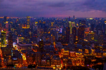 Obraz premium aerial view of the Shanghai city skyline at night illuminated by numerous lights and neon signs, specifically around the Bund and Nanjing Road areas