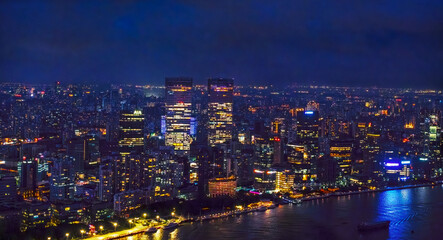 Obraz premium aerial view of the Shanghai city skyline at night illuminated by numerous lights and neon signs, specifically around the Bund and Nanjing Road areas