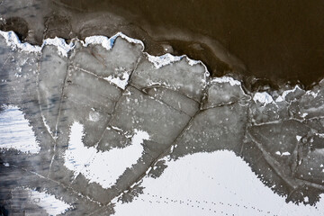 The texture of a frozen lake and pieces of floating ice in the water. Winter landscape from a drone.
