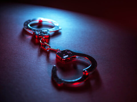 Handcuff under red and blue light symbolizing crime and punishment