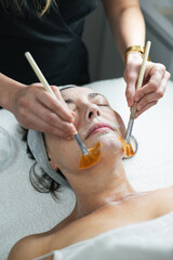 Esthetician applying cleansing mask on woman's face