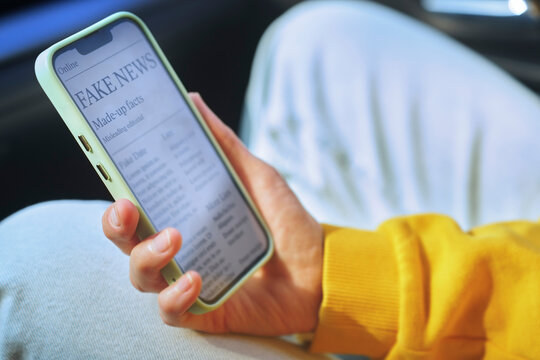 Person reading fake news on smartphone inside a car