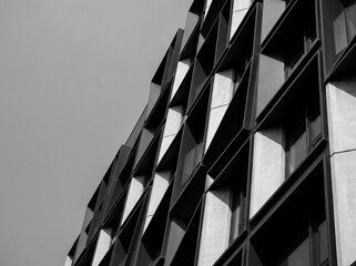 Modern black and white abstract architecture detail of a tall glass business skyscraper facade reflecting the urban city sky