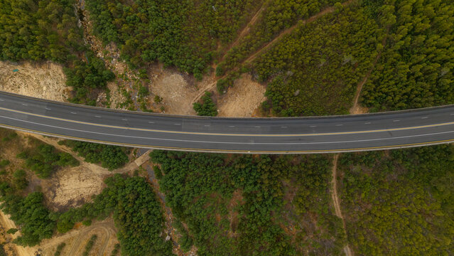 Aerial view of a modern highway bridge gracefully spans across a rugged landscape, a stark contrast of smooth asphalt and untamed nature, Paarl, Western Cape, South Africa.