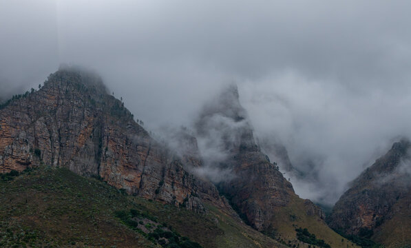 Aerial view of rugged mountains shrouded in ethereal mist, creating a dramatic contrast of light and shadow, Paarl, Western Cape, South Africa.