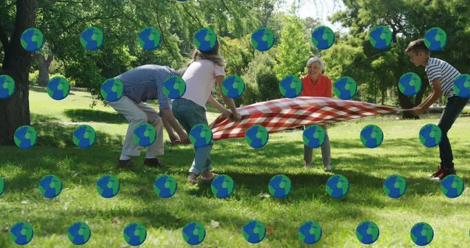 Animation of globe icons over caucasian family making picnic