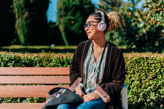 Tourist relaxing on bench listening to music outdoors in Madrid