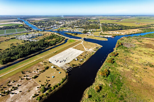 Aerial view of dark water flowing into the canal creating a striking contrast with the surrounding greenery, Lake Okeechobee, Moore Haven, Florida, United States.