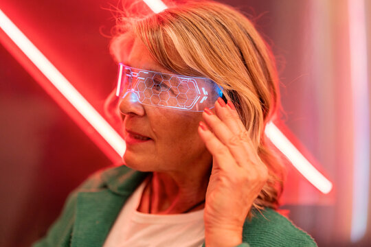 Woman wearing futuristic VR headset in neon illuminated setting