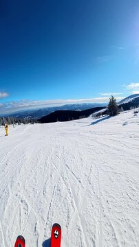 Travel and winter adventure concept. Beautiful POV ski landscape on the mountains. Skier skis down a snowy mountain trail in cloudy weather. Vertical shot in slow motion