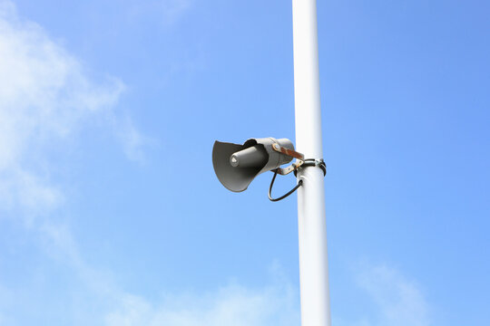 Damaged loudspeaker on pole against blue sky in Austria outdoors