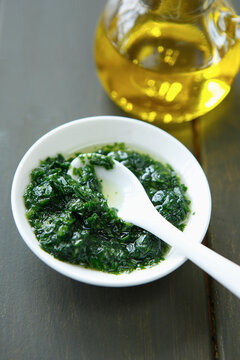 Wild garlic pesto with basil and oil in a white bowl on table