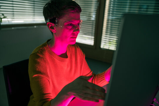Woman in modern office using VR glasses and computer