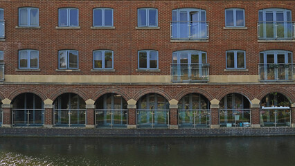 Fototapeta premium Exterior of brick Flats house object on Regents Canal in London, England. Real estate, residential apartments and offices. Living apartments or office building architecture