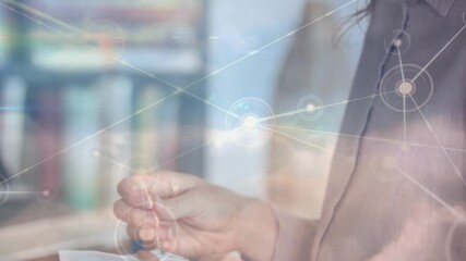 Mid-adult woman engaging with virtual network interface in tech office, showing glowing nodes - Powered by Adobe