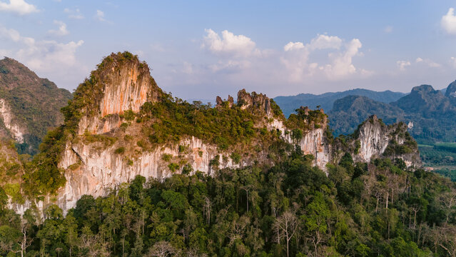 Aerial view of towering limestone cliffs pierce through the lush green canopy, a symphony of textures and tones under the soft sky, Khao Sok National Park, Surat Thani, Thailand.