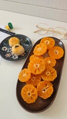 Fresh Fruit Delights: A close-up view presents an artistic arrangement of vibrant orange tangerine slices and a small plate of pastries, creating an appealing still life of food.
