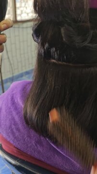 Haircut in progress: A glimpse into a beauty treatment as a hair stylist meticulously cuts and styles the hair, focusing on precision and aesthetic.