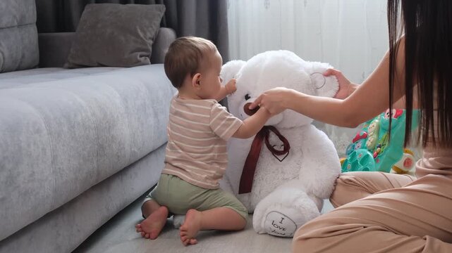 Little boy is playing with teddy bear and his mom in their home.