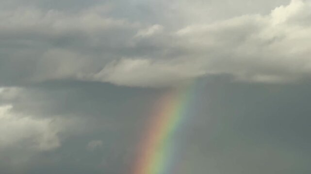 Rainbow over landscape. Rainbow over landscape under cloudy sky.