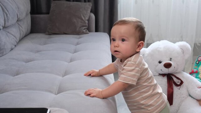 Happy child boy is learning to walk with his mom and playing n their home.